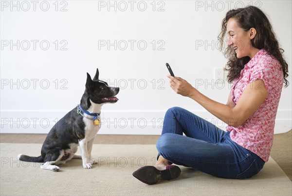 Young woman taking photograph of her dog.