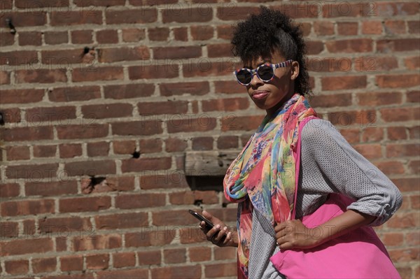 Young woman against brick wall.