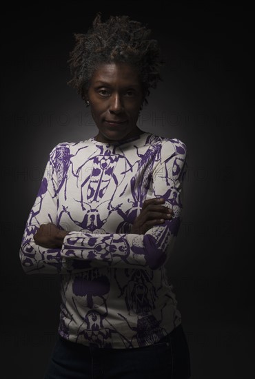 Studio shot of woman standing with arms crossed.