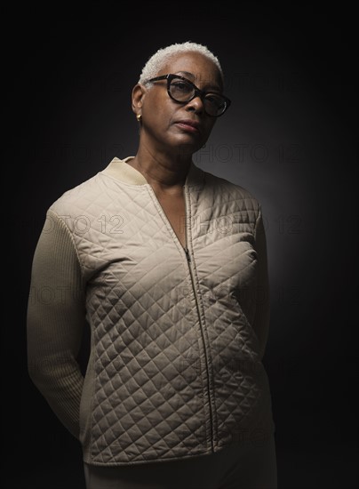 Studio shot of woman standing with hands behind back.