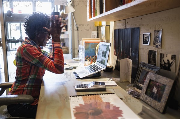 Woman gesturing in front of laptop in office.