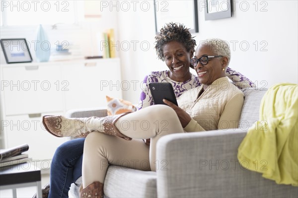 Smiling women using tablet in living room.