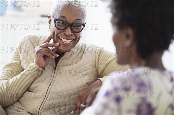 Smiling women sitting and talking in living room.