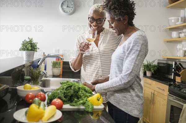 Two women cooking in domestic kitchen.