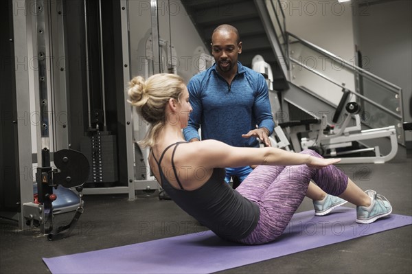 Woman exercising with personal trainer in gym.