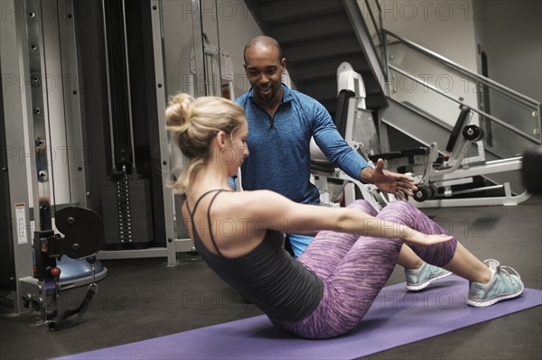 Woman exercising with personal trainer in gym.