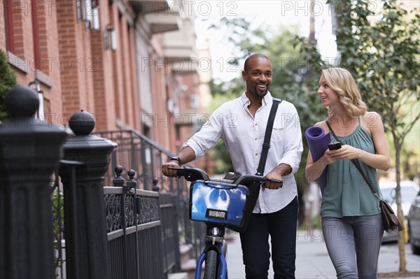 Couple walking with bicycle and exercising mat.