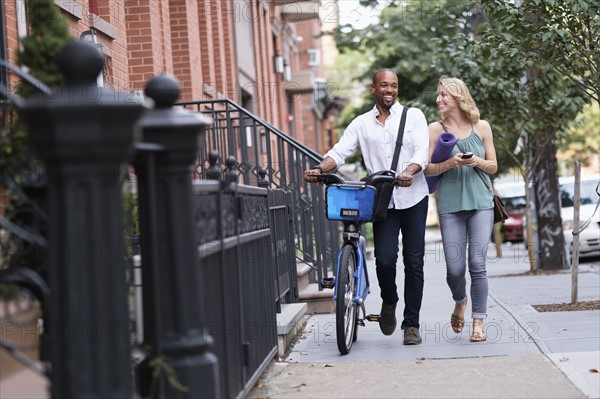 Couple walking with bicycle and exercising mat.