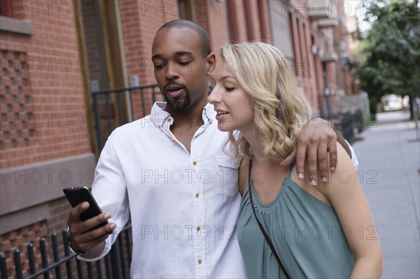 Couple looking at mobile phone during walk.