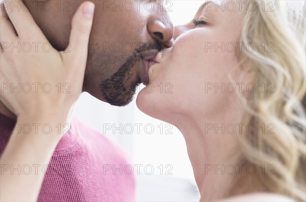 Multi ethnic couple kissing.