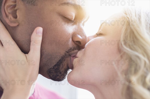 Multi ethnic couple kissing.