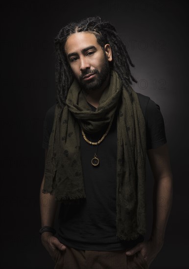 Portrait of man with dreadlocks on black background.