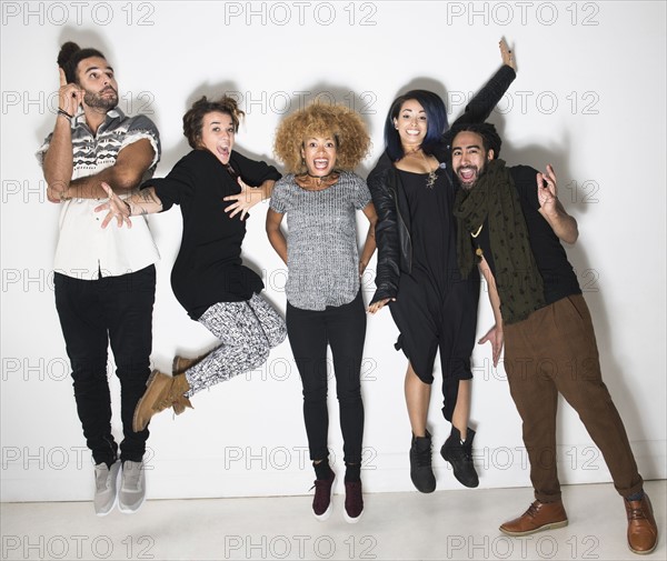 Portrait of group of happy friends against white wall.