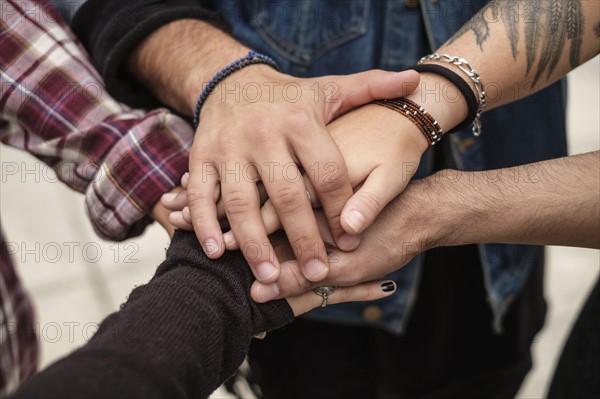 Stack of hands, friends holding hands outdoors.