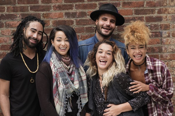 Portrait of happy friends against brick wall.