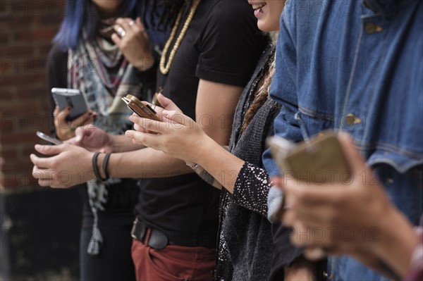 Young people standing in row using smartphones.