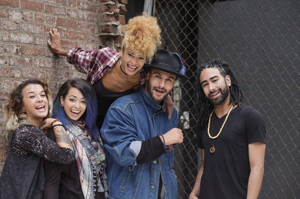 Portrait of happy friends against brick wall.