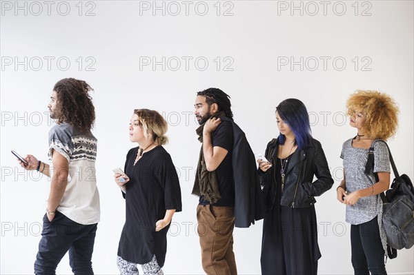 Young people standing in line using smartphones.