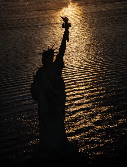 USA, New York State, New York City, Silhouette of Statue of Liberty at sunrise.