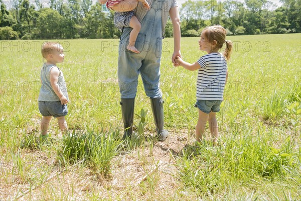 USA, Pennsylvania, Washington Crossing, Mother with three daughters (18-23 months, 2-3) walking on green field