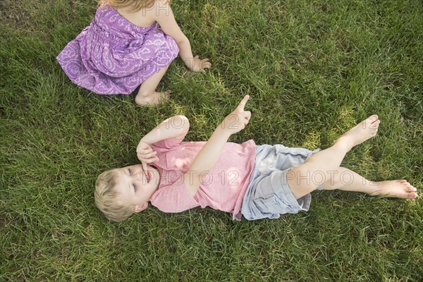 Boy (4-5) and girl (2-3) lying on grass