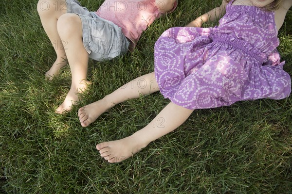 Boy (4-5) and girl (2-3) lying on grass