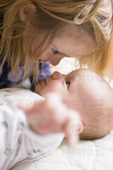 Girl (2-3) face to face with baby brother (6-11 months)