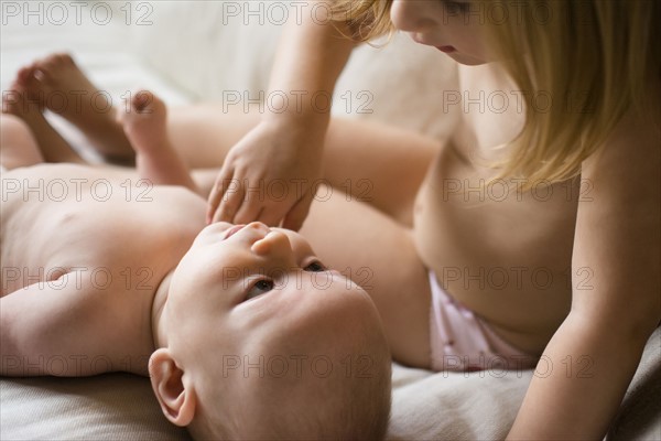 Girl (2-3) looking at baby brother (6-11 months) on bed