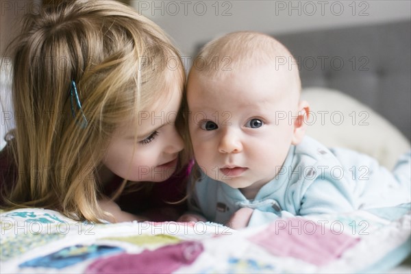 Sister (2-3) and brother (6-11 months) lying on bed