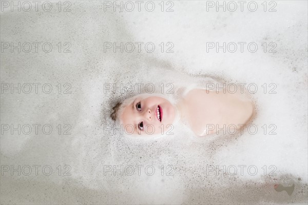 Girl (2-3) lying in bathtub