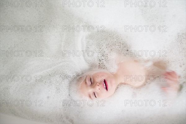 Girl (2-3) lying in bathtub