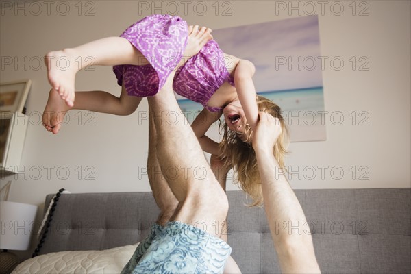 Father lifting daughter (2-3) with legs