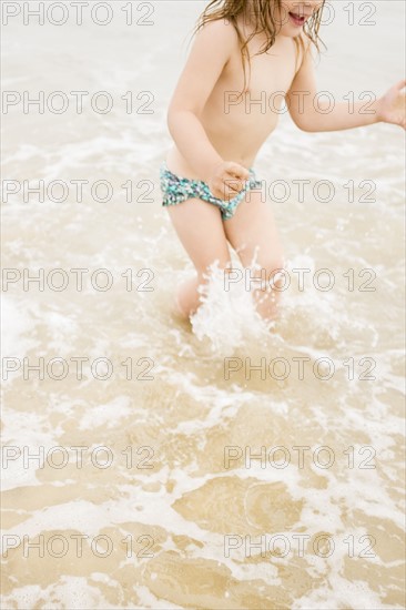 Girl (2-3) wading in ocean and splashing