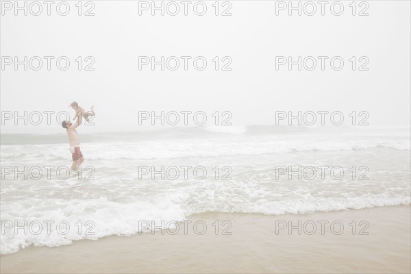 USA, New York, Monatuk, Father and daughter (2-3) on beach by ocean