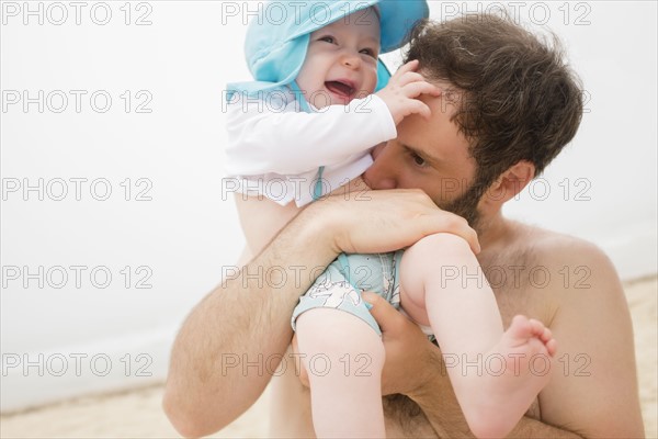 Father kissing baby son (6-11 months) on stomach