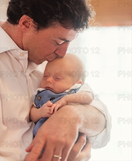 Father kissing baby son (0-1 months)