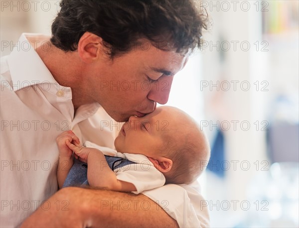 Father kissing baby son (0-1 months)