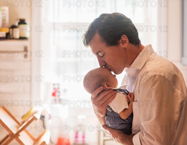 Father kissing baby son (0-1 months)