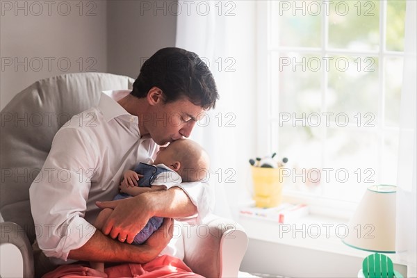 Father kissing baby son (0-1 months) by window