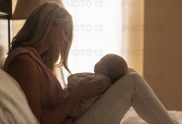 Mother holding son (0-1 months) in bedroom