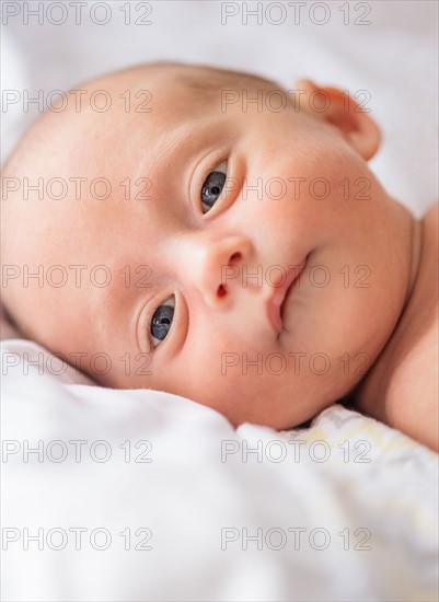 Baby boy (0-1 months) lying on bed