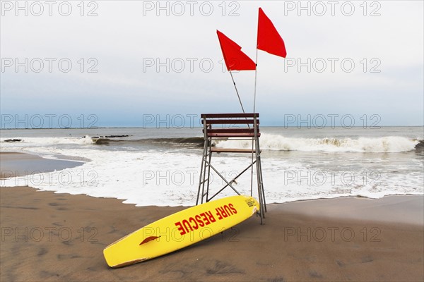 USA, New York State, New York City, Brooklyn, Yellow surfboard and empty lifeguard stand on beach