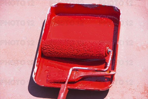 Paint roller in tray with red paint