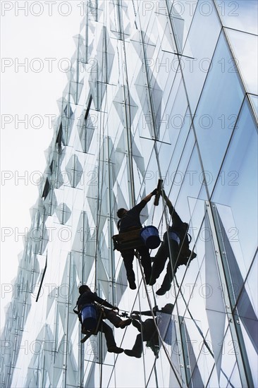 USA, New York, New York City, Windows washers cleaning glass facade of office building