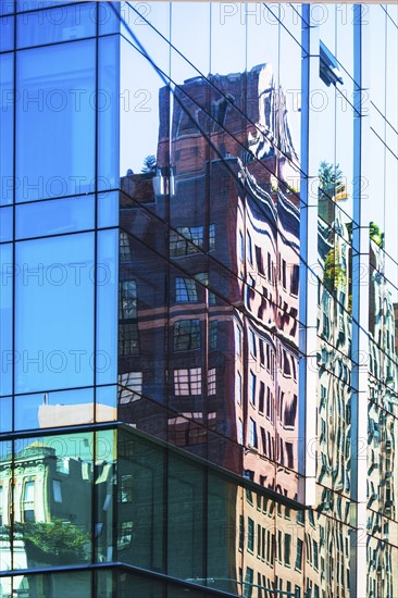 USA, New York, New York City, Building reflected in glass facade of office building