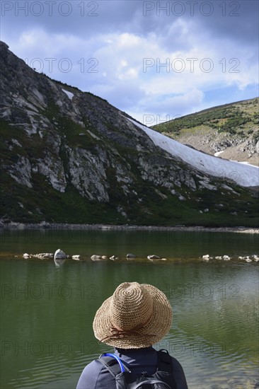 USA, Colorado, Idaho Springs, Hiker sitting by lake below Saint Mary's Glacier