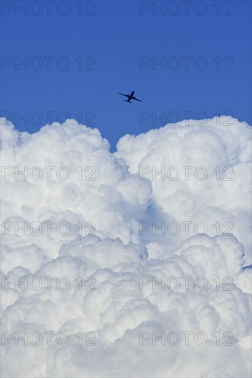 Airplane flying over large cloud