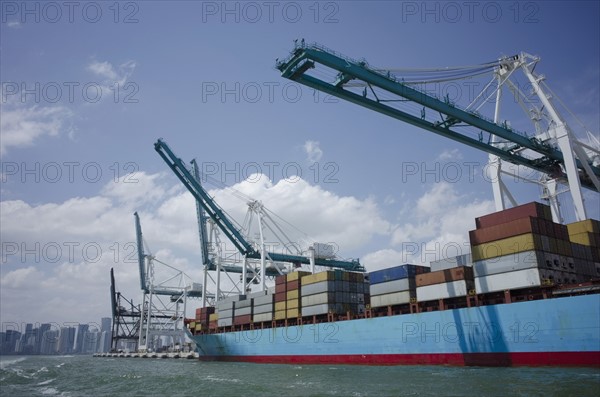 USA, Florida, Miami, Container ship with cranes and city skyline in background