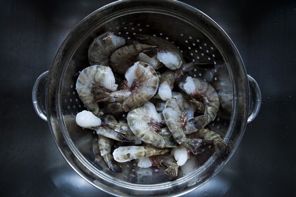 Frozen prawns in metal colander