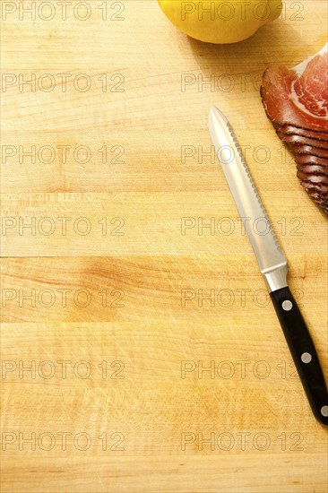 Spoon, lemon and slices of meat on cutting board